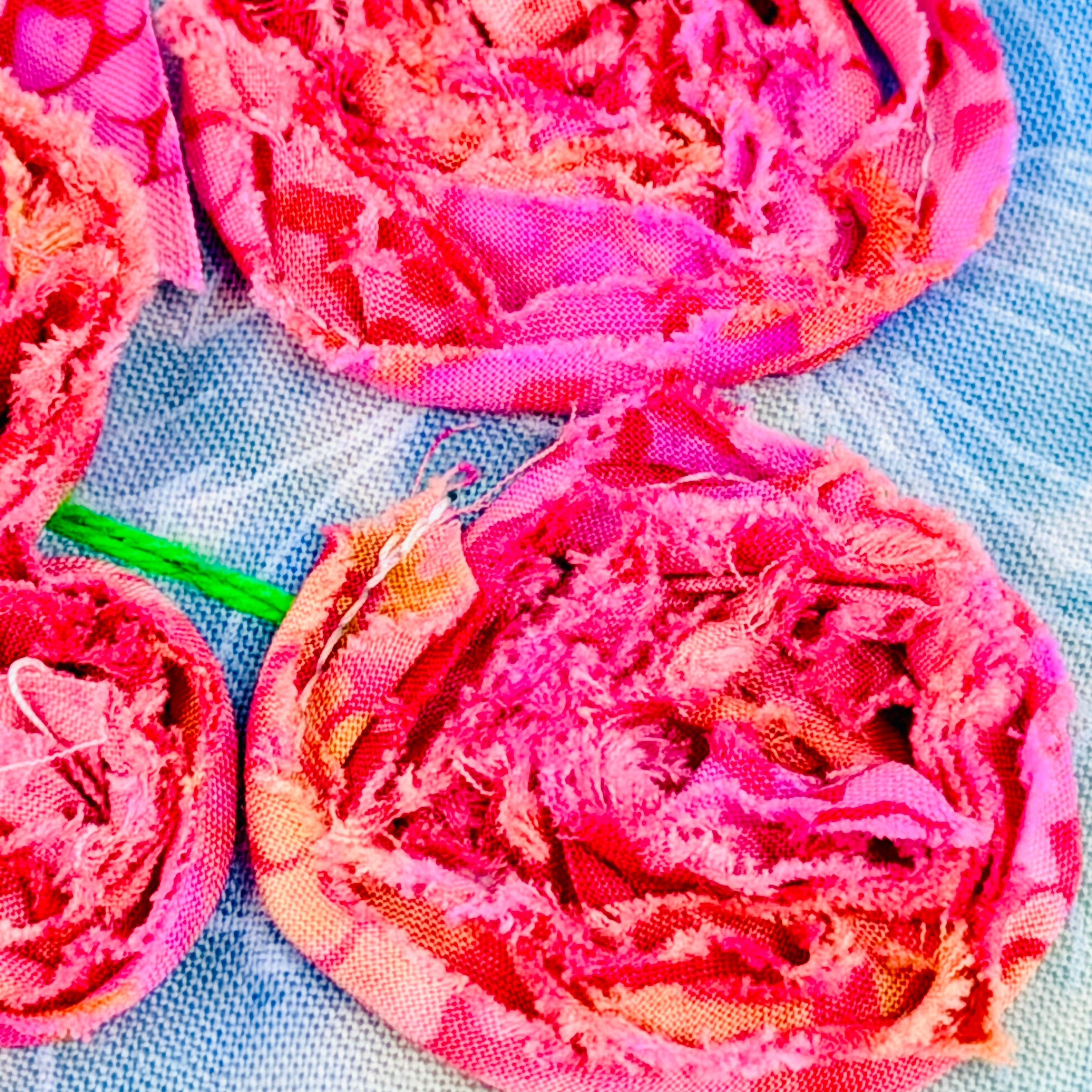 Pink fabric flowers on a blue textured surface