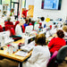Group of people working on sewing machines in a classroom setting.