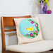 Decorative pillow with a floral design and yellow bird on a chair in a room setting.