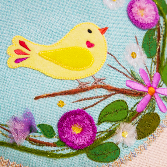 Embroidered design of a yellow bird and flowers on fabric