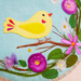 Embroidered design of a yellow bird and flowers on fabric
