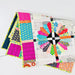 A folded patchwork quilt with a colorful geometric and floral pattern, displayed on a clean white surface.