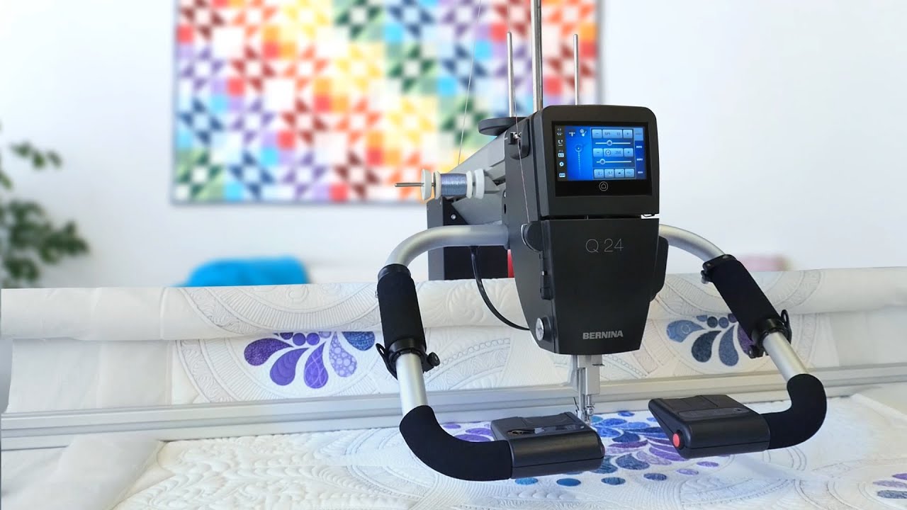 Gaming console with a screen attached to a stand on a bed with a colorful painting in the background.