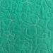 A close-up of a green quilted fabric featuring stitched floral and abstract leaf patterns in a contrasting light beige or cream thread.