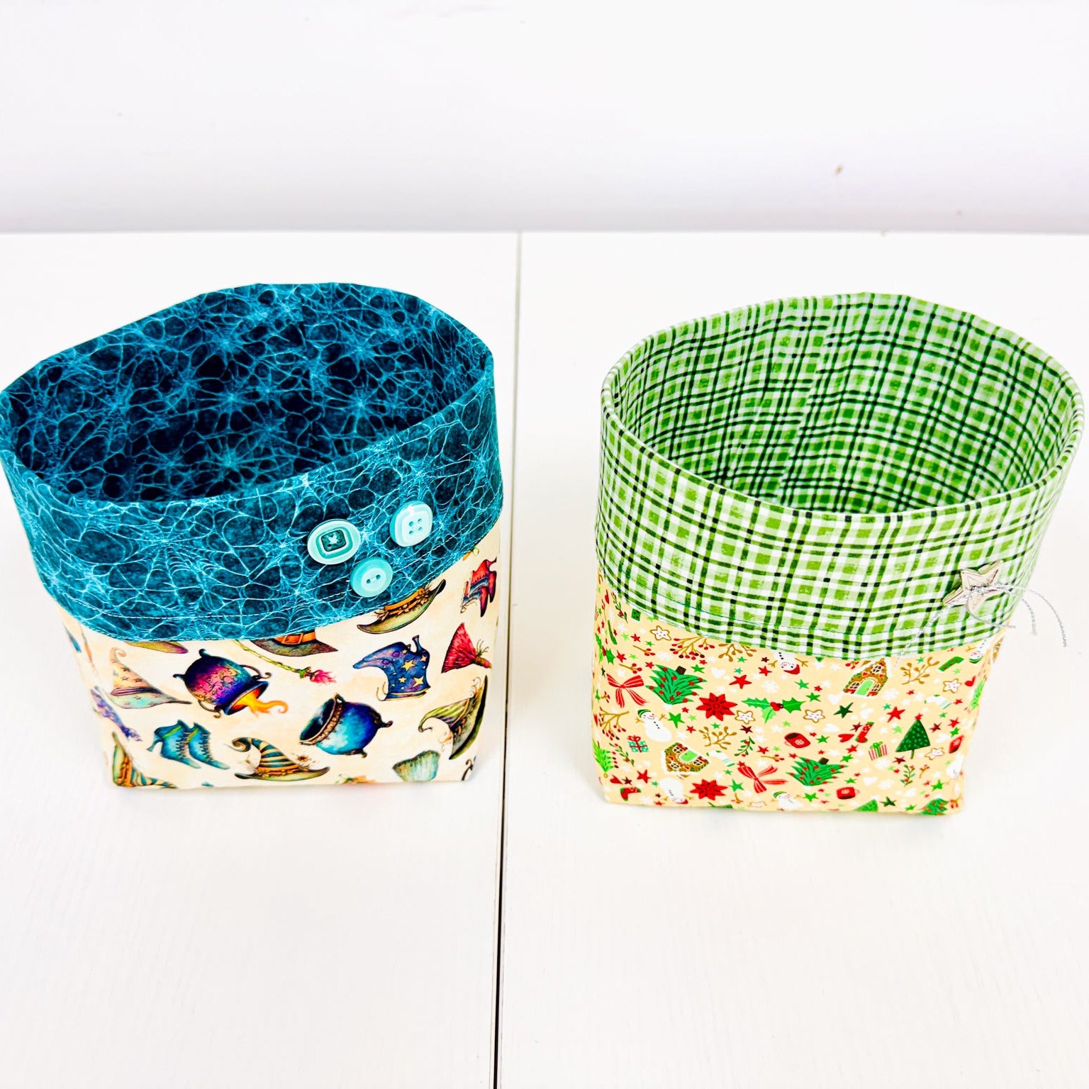 Two fabric storage baskets on a white surface against a white background. The left basket has a blue marbled top and a multicolor fish-patterned bottom with two blue buttons.