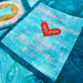 Close-up of a quilt with embroidered text and heart design on a blue background