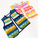 Two sleeveless patchwork vests laid flat on a white background. The front vest is navy blue with horizontal stripes of yellow, green, and orange, featuring a shark pattern.