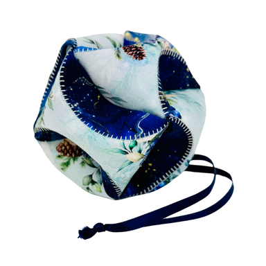 A fabric drawstring pouch with a light blue and navy blue winter forest print, featuring pinecones and white flowers, with a navy blue drawstring cord.