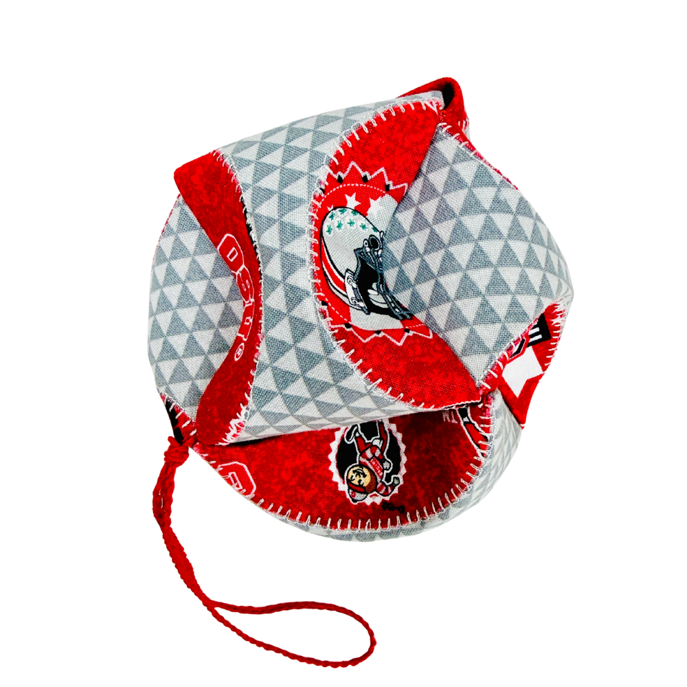 A small soft fabric cap or pouch with a red and white geometric pattern, red trim, and printed cartoon graphics, shown on a plain white background.