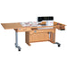 A white, height adjustable sewing table with an electric lift and a filler panel, equipped with wheels for mobility.