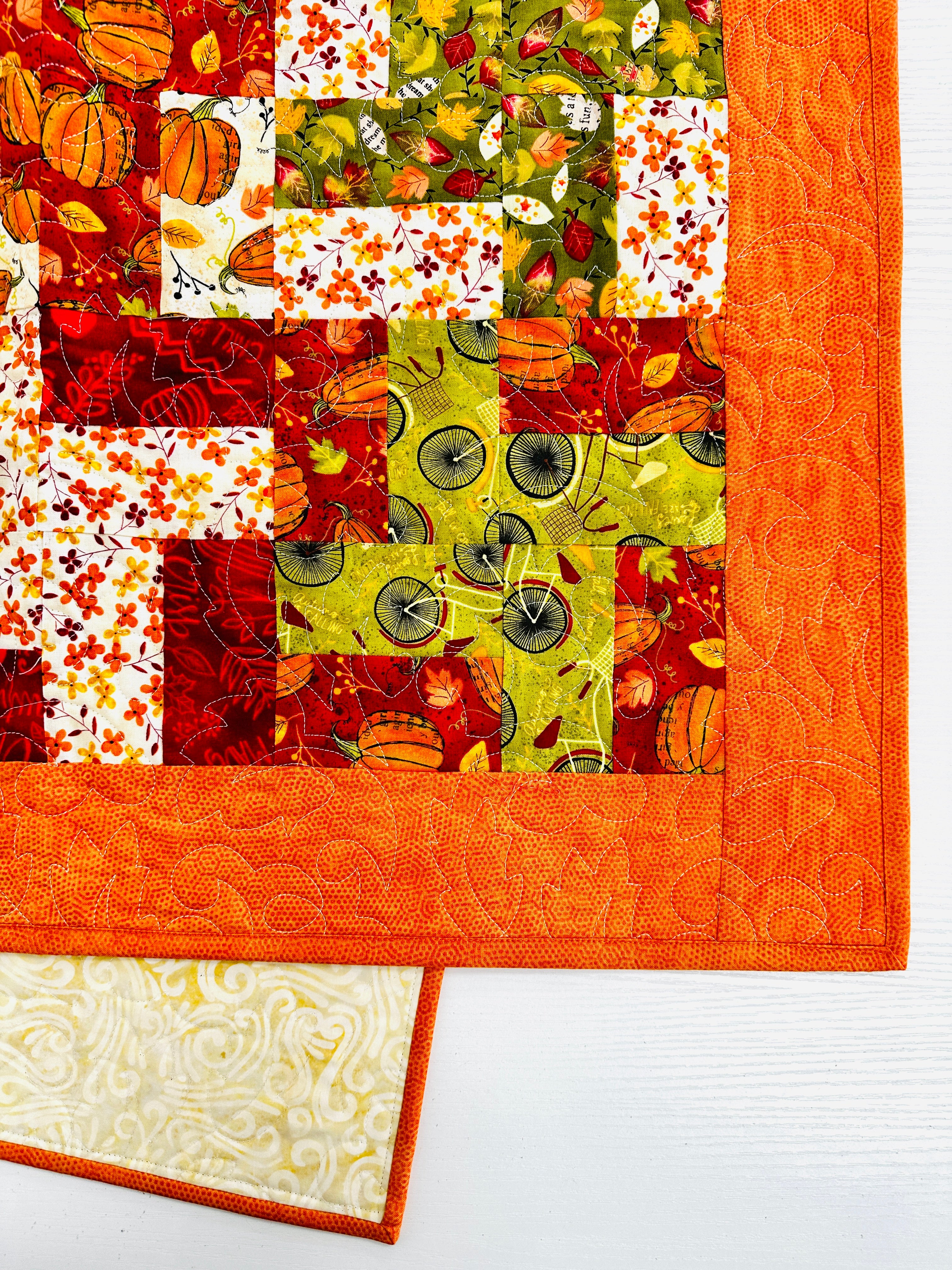 Colorful quilt with autumn-themed patterns on a white background