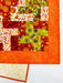 Colorful quilt with autumn-themed patterns on a white background
