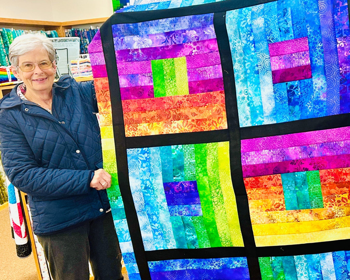 Person holding a colorful quilt with geometric pattern in a fabric store.