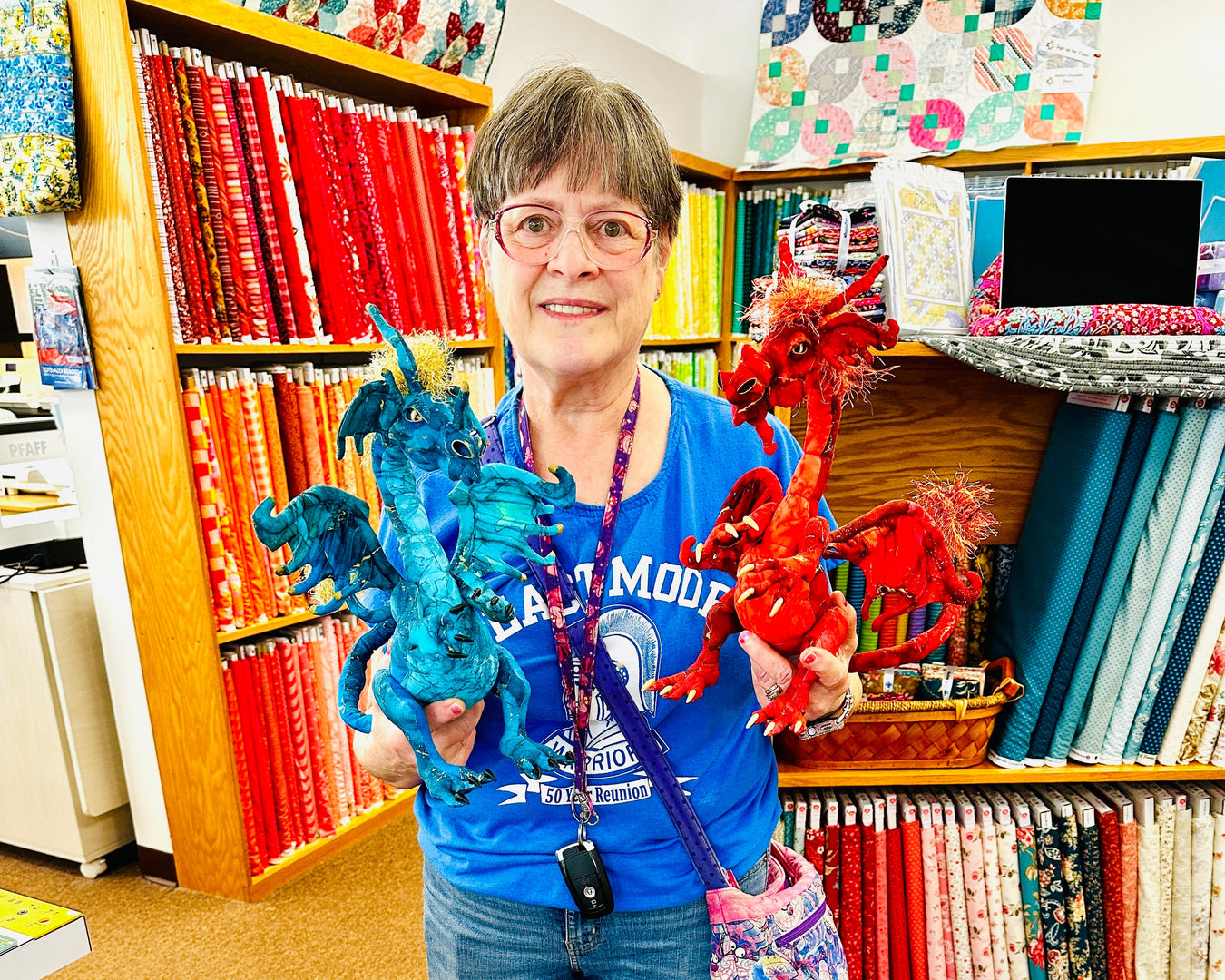 Person holding colorful dragon toys in a store with shelves of books and products.