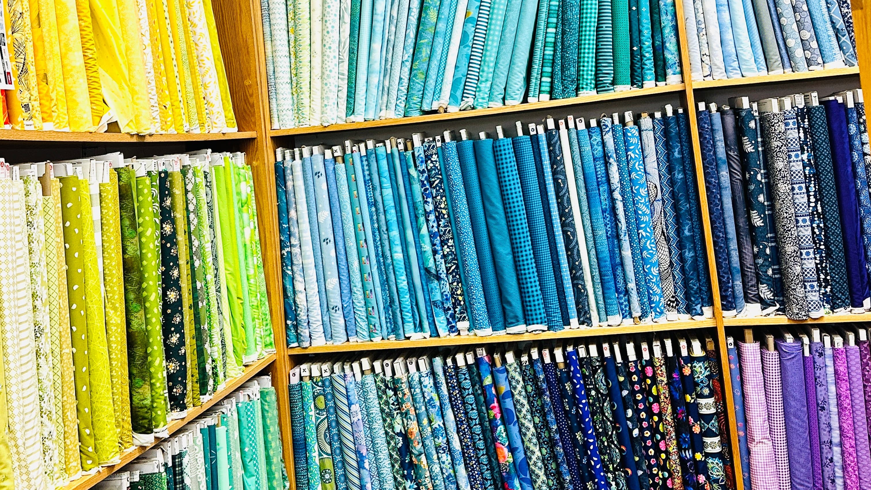 Display of colorful fabric rolls and quilts in a store.