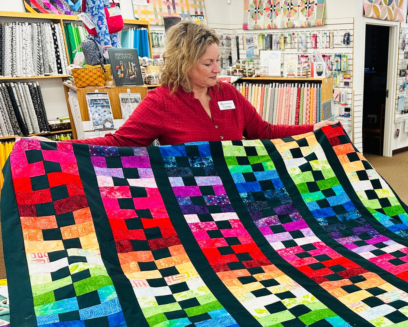 Two women with a colorful quilt in a store setting