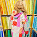 Person wearing a colorful quilted jacket in a fabric store