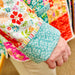 Colorful quilt with floral patterns held by a person.