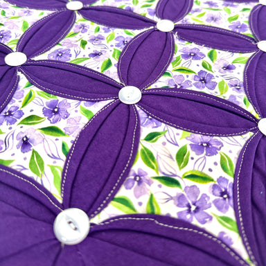 Close-up of a purple floral design with white buttons on a floral background