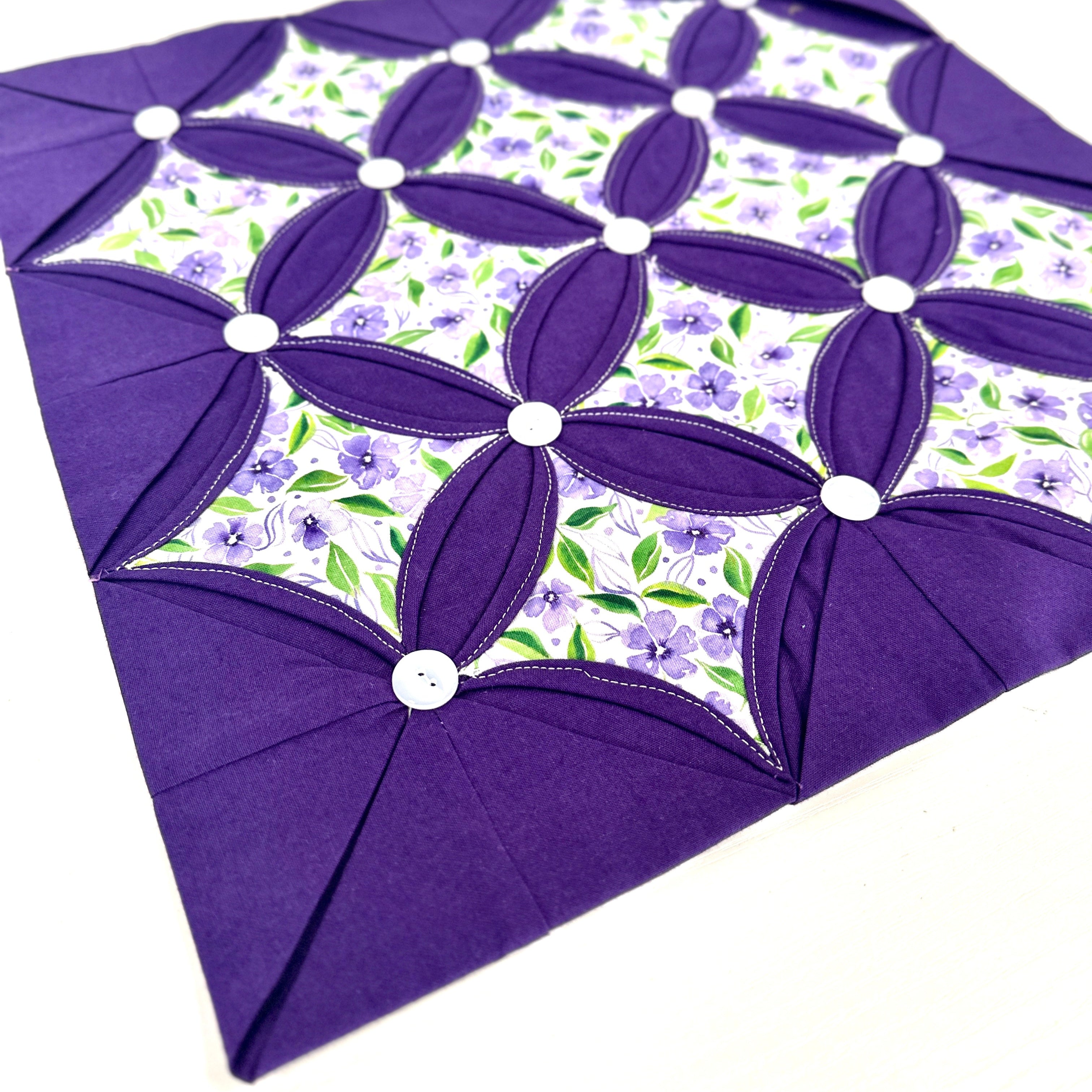 Purple quilt block with floral pattern on a white background