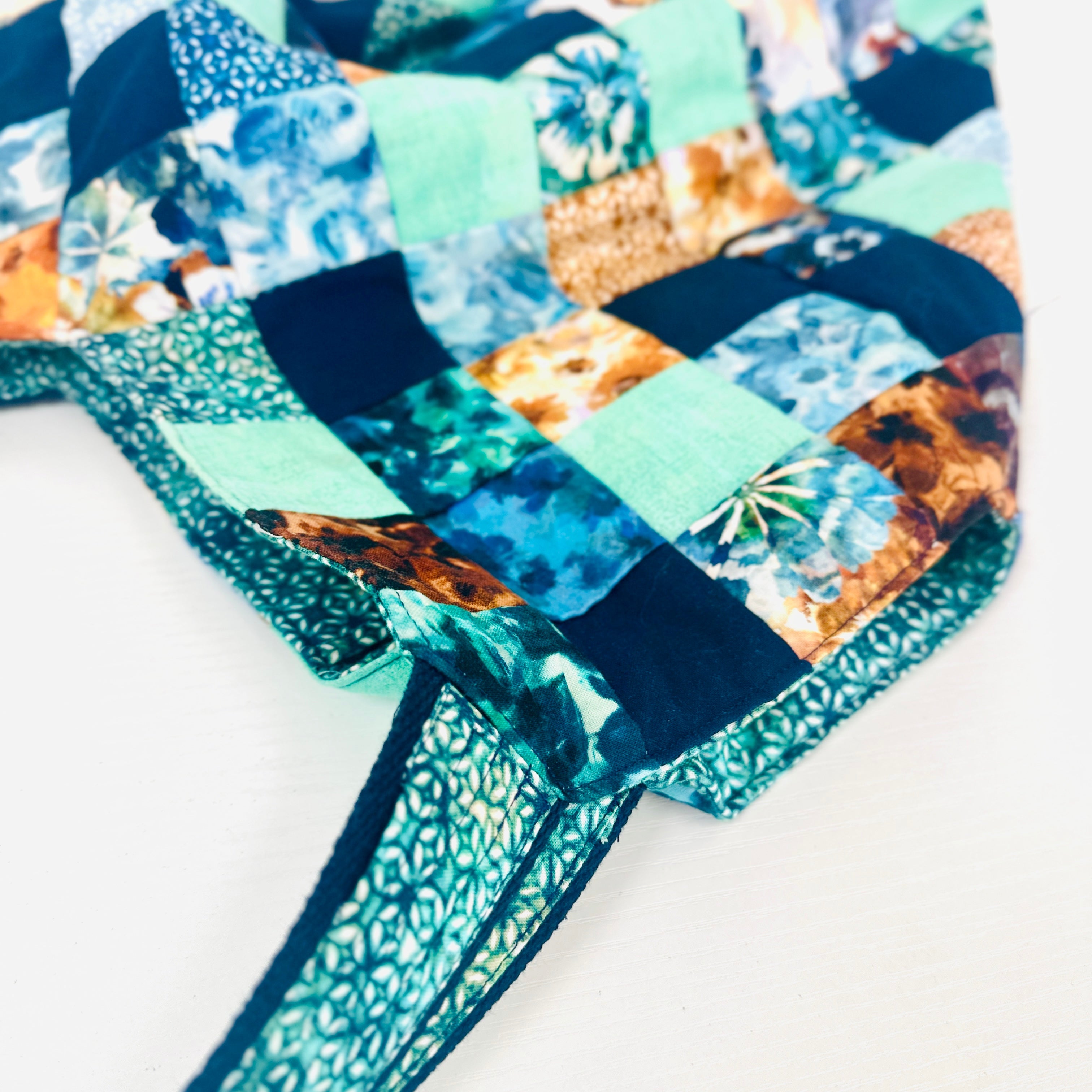 Patchwork quilt with blue and green patterns on a white background