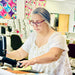 Two women working on a sewing machine in a store setting.
