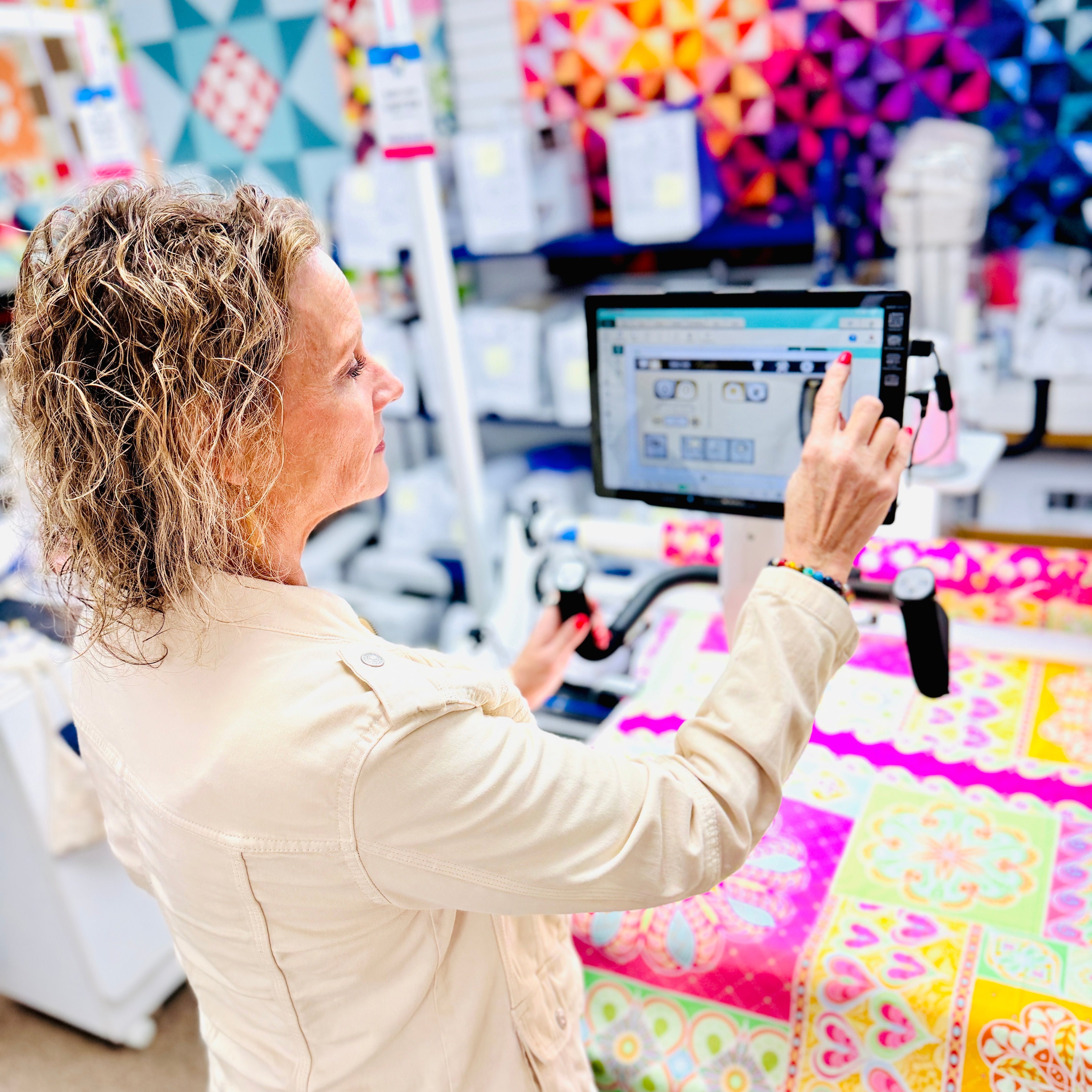 Woman using a computer in a fabric store with colorful quilts in the background