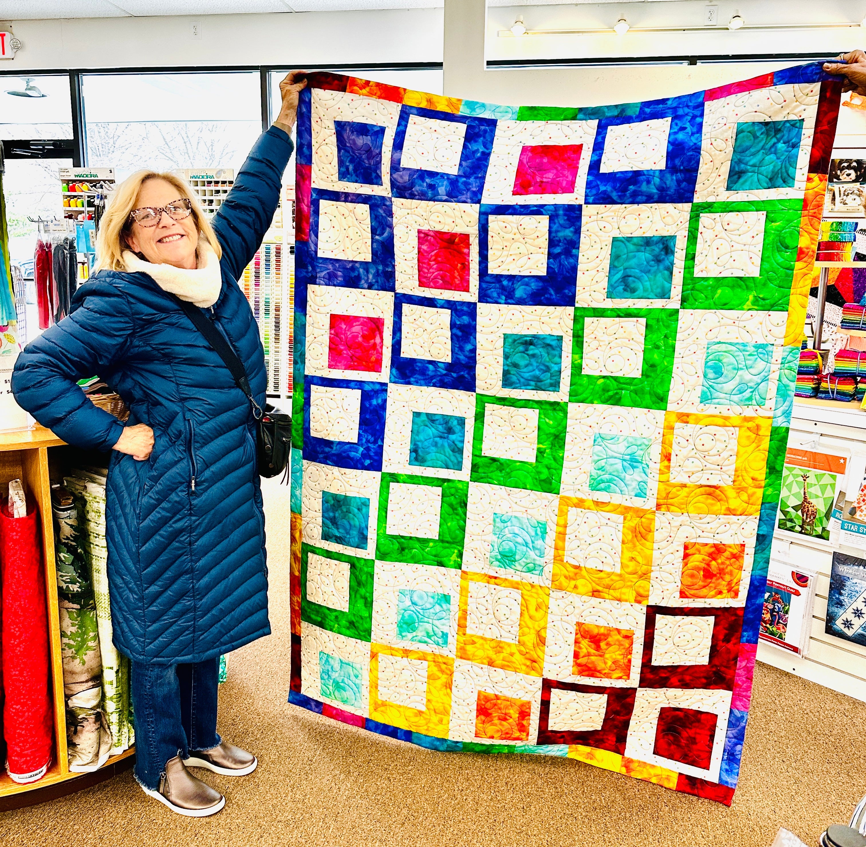 Woman holding a colorful quilt in a store setting