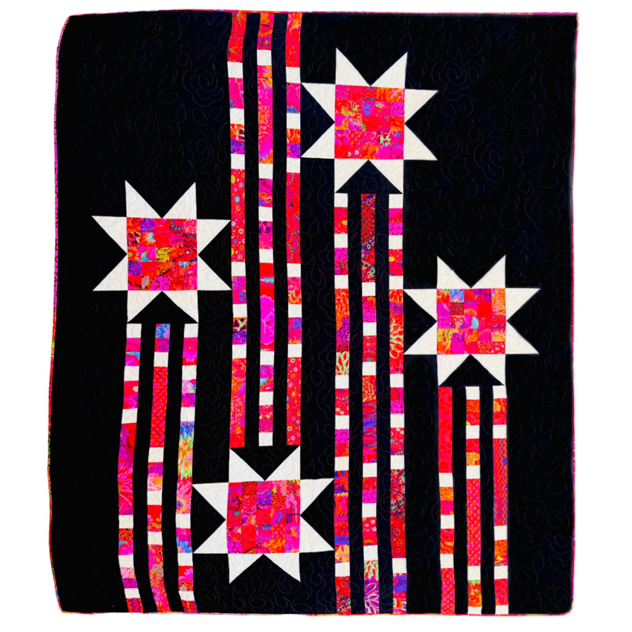 A square quilted textile featuring a black background with four starburst motifs in white and bright pink, red, orange, and purple patterned fabric, connected by vertical striped columns in pink, white, and black.