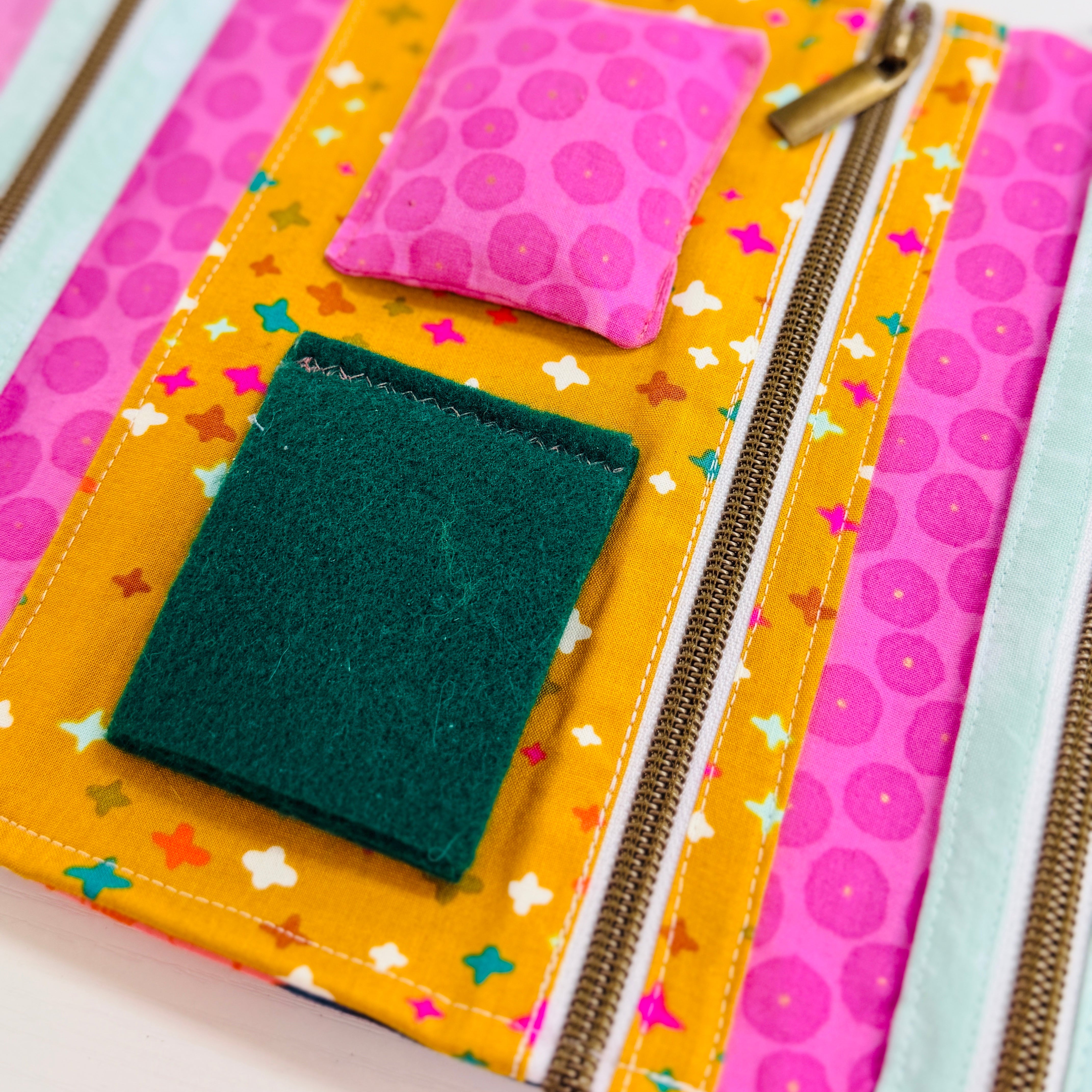 Colorful fabric pouch with a green pocket and pink floral pouch on a white background