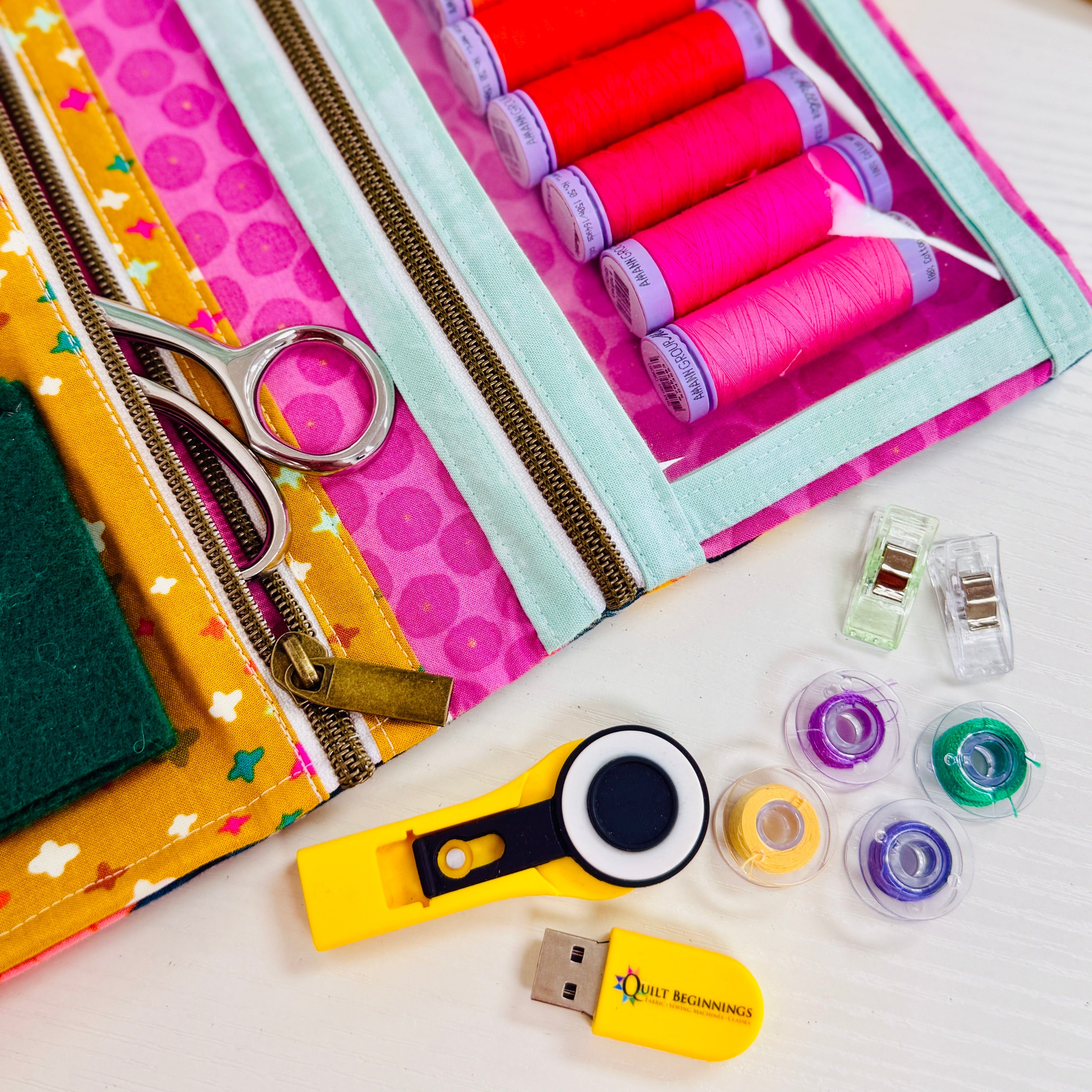 Sewing kit with colorful thread spools, scissors, and other tools on a white background