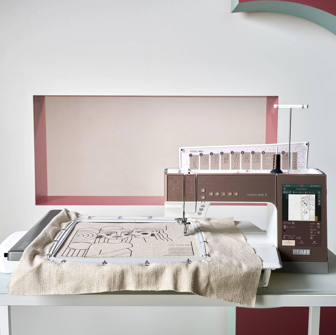 Commercial embroidery machine on a table with a colorful abstract painting in the background